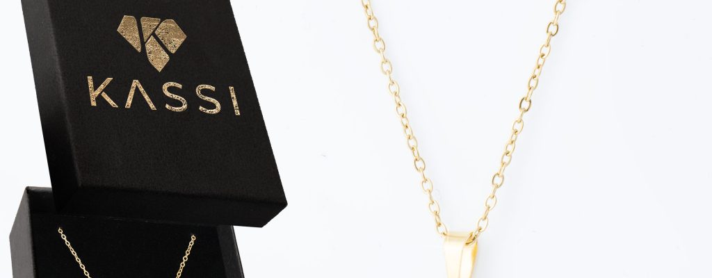 Elegancki pozłacany naszyjnik choker Kassi ułożony blisko szyi na jasnym tle